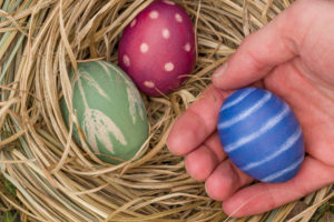 Hand holding blue and white striped Easter egg Hand holding blue and white striped Easter egg